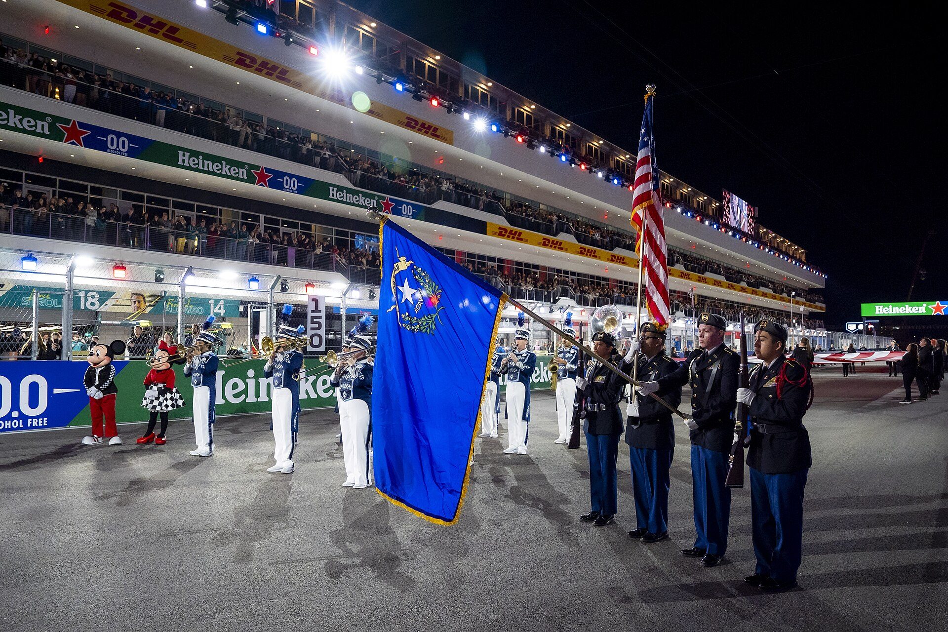 Colour guard on the grid in front of the pit building grandstand at night, 2025 Las Vegas Grand Prix